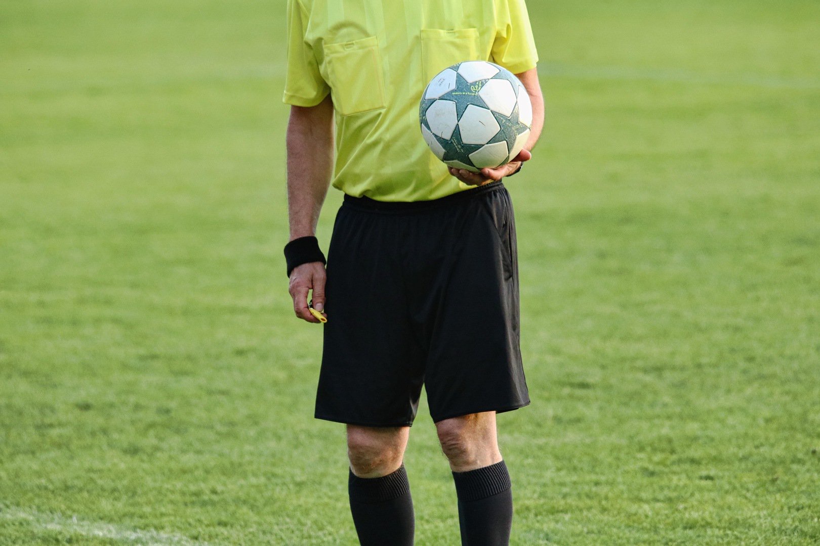 Schiedsrichter hält einen Fußball in der Hand