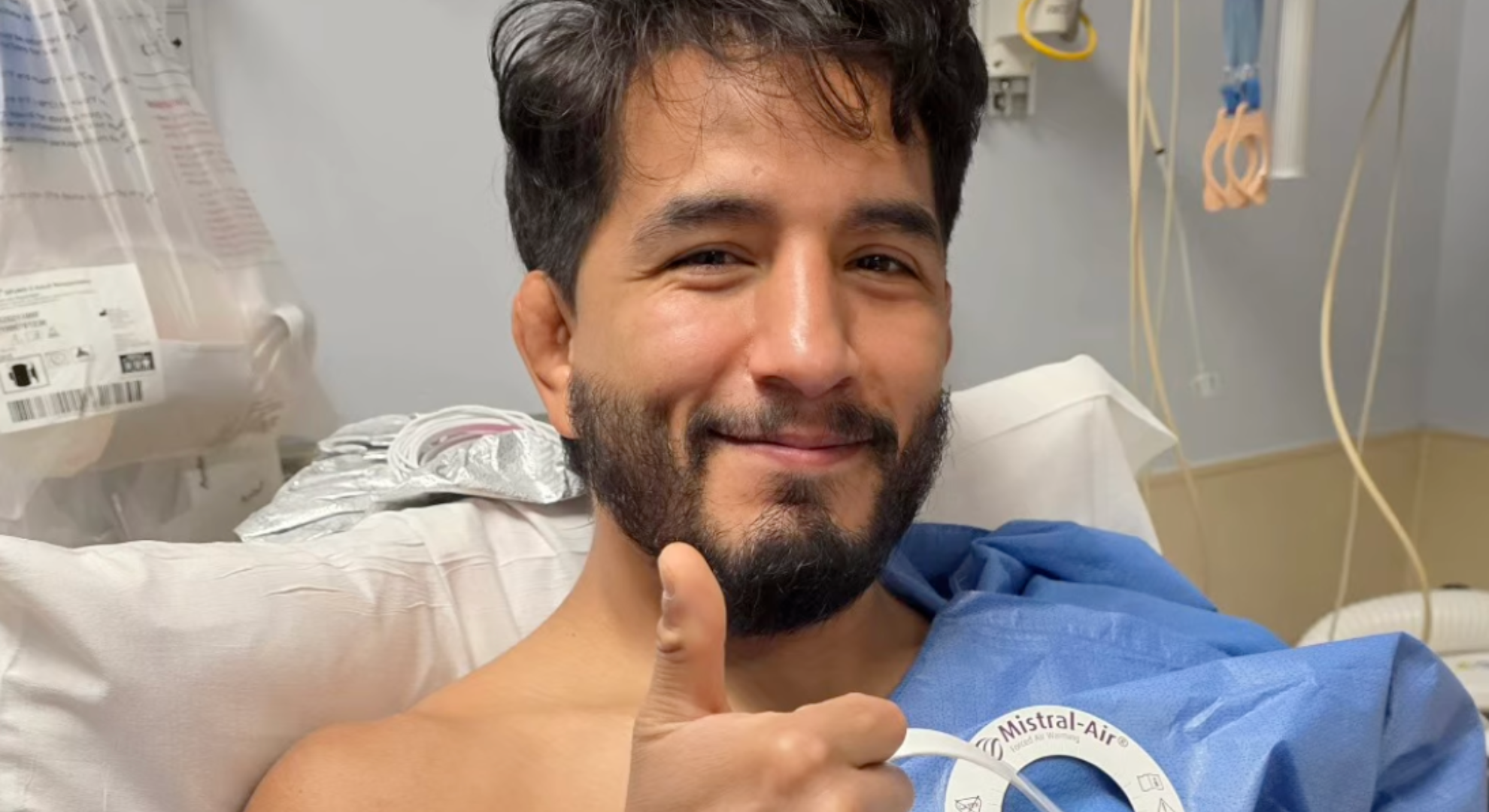 Adrian Yanez gives a thumbs up as he lies in a hospital bed