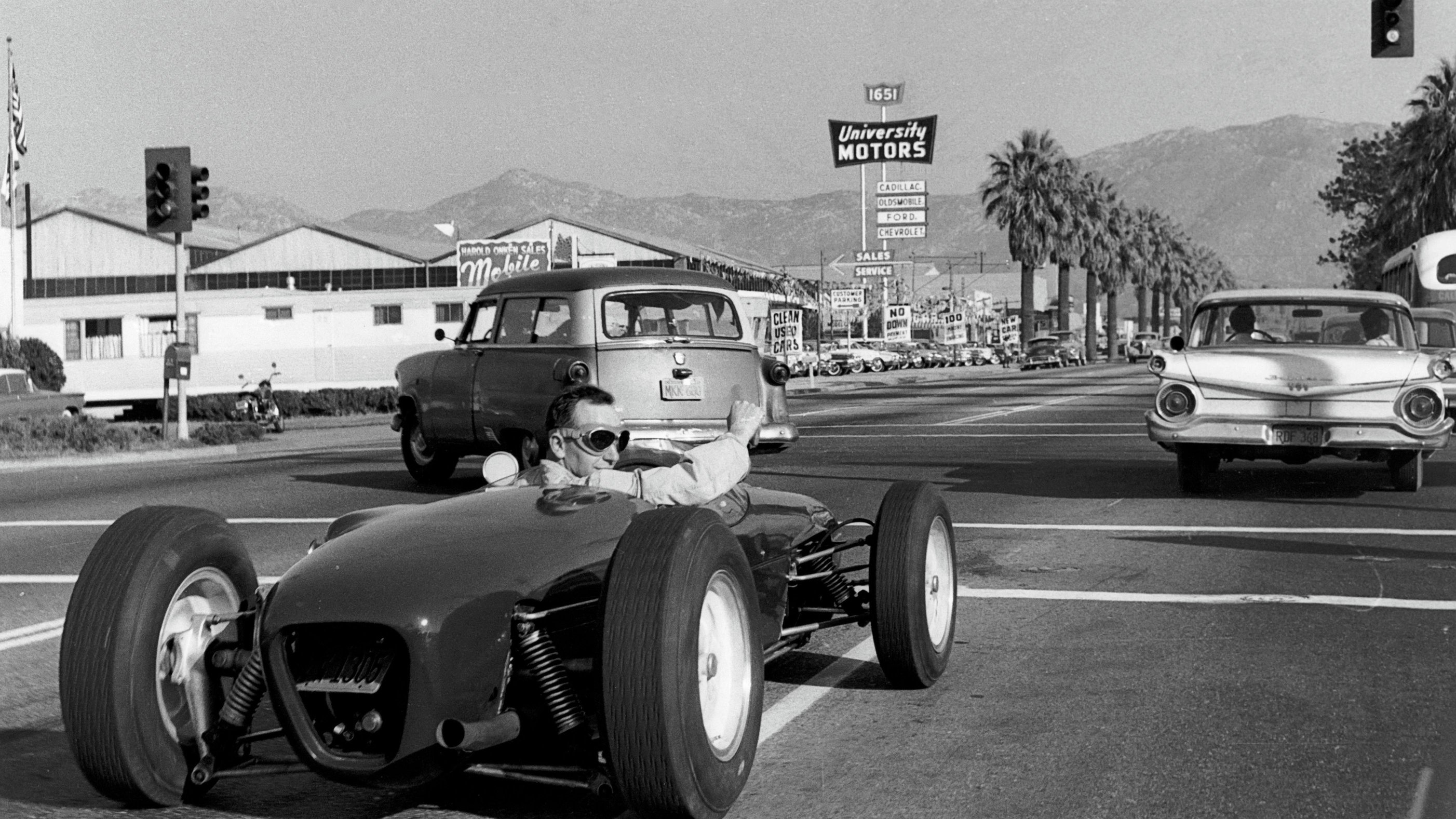 John Surtees drives his Lotus on a public highway to the 1960 US Grand Prix at Riverside in California