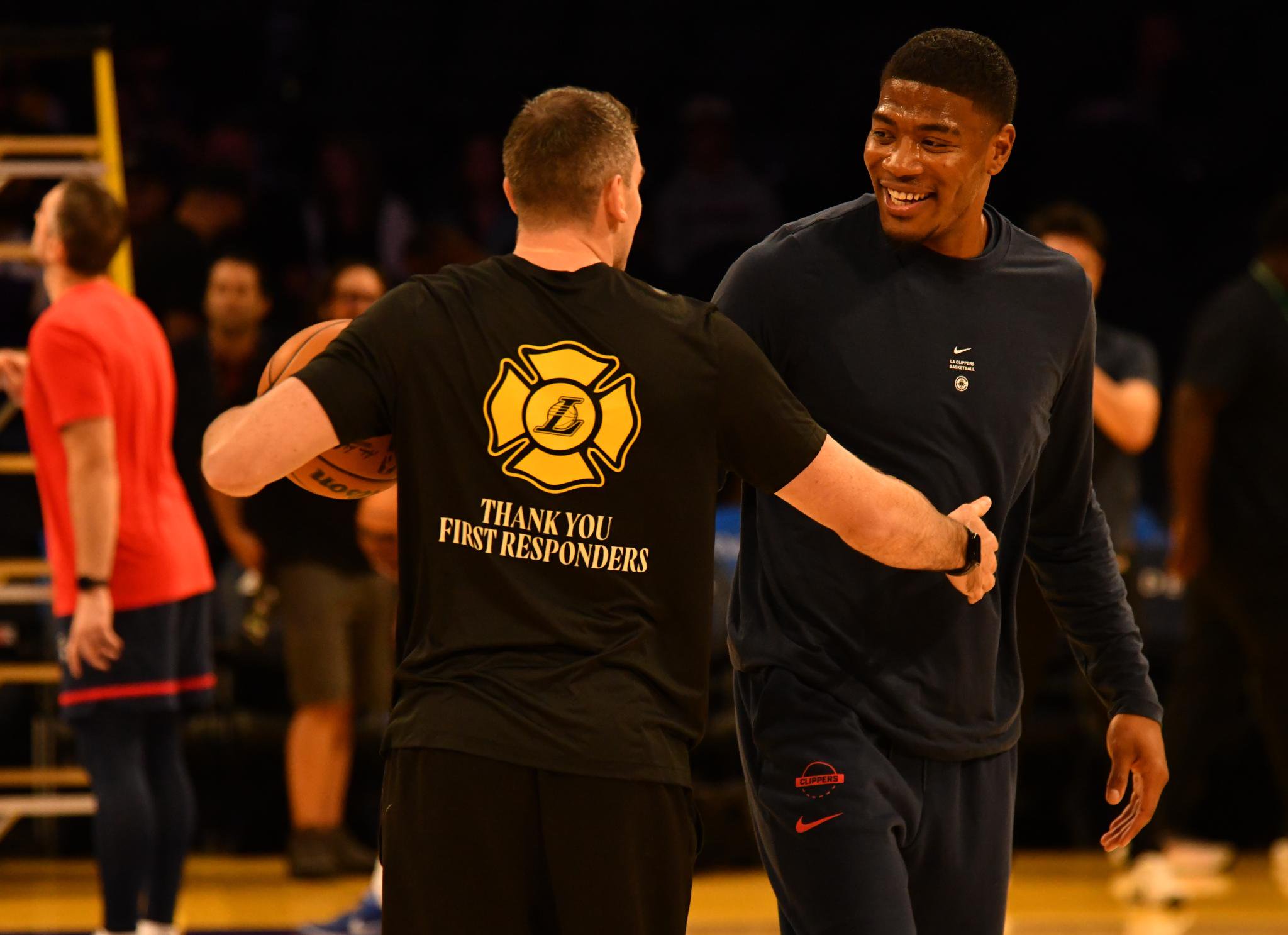 Rui Hachimura smiling and shaking hands with another man during warmups.