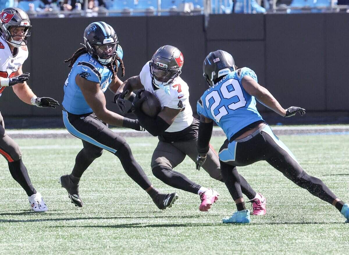 Tampa Bay Buccaneers running back Bucky Irving carries the ball through Carolina Panthers offensive linebacker Pat Jones II, left, and cornerback Akayleb Evans on Sunday, Oct. 25, 2026 at Bank of America Stadium in Charlotte.