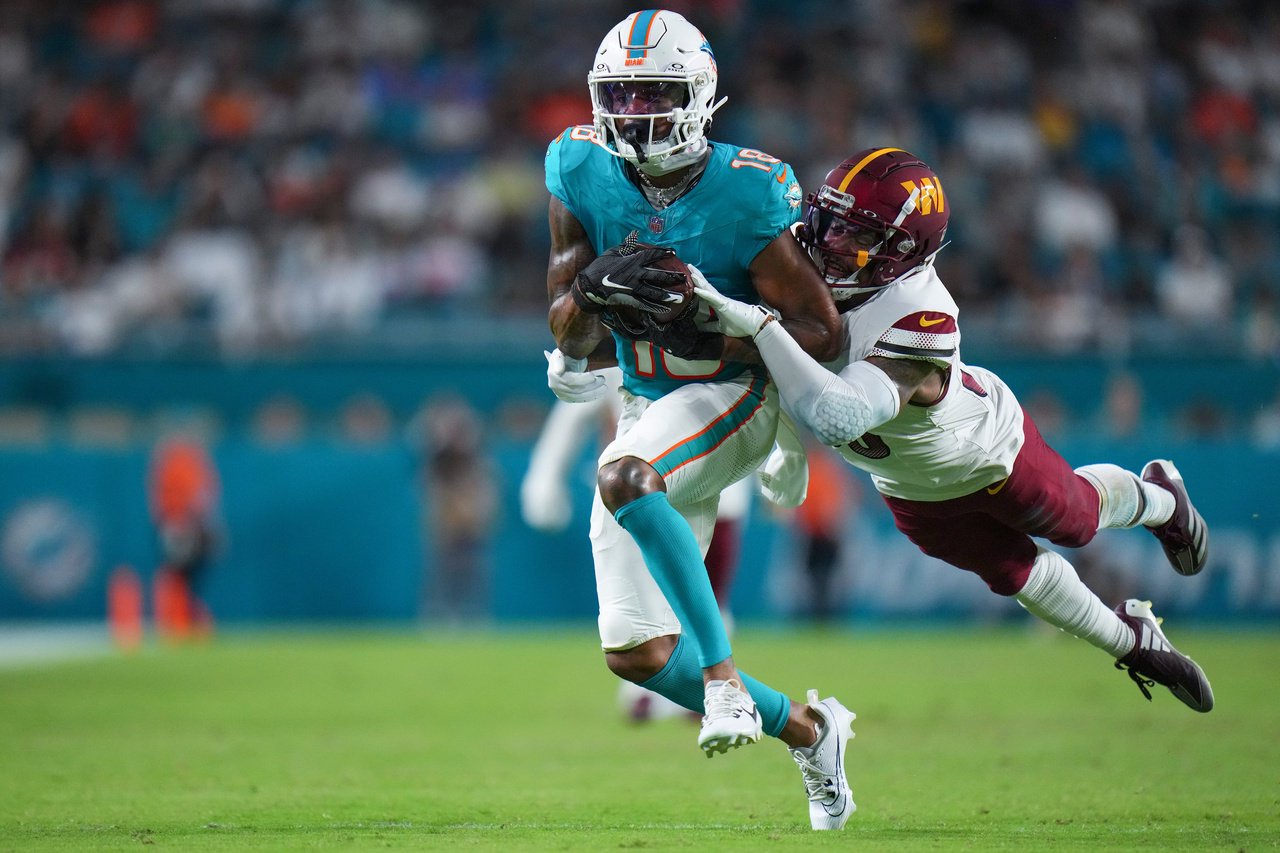 MIAMI GARDENS, FLORIDA - AUGUST 17: A.J. Woods #38 of the Washington Commanders tackles Erik Ezukanma #18 of the Miami Dolphins during the third quarter in a preseason game at Hard Rock Stadium on August 17, 2024 in Miami Gardens, Florida. 