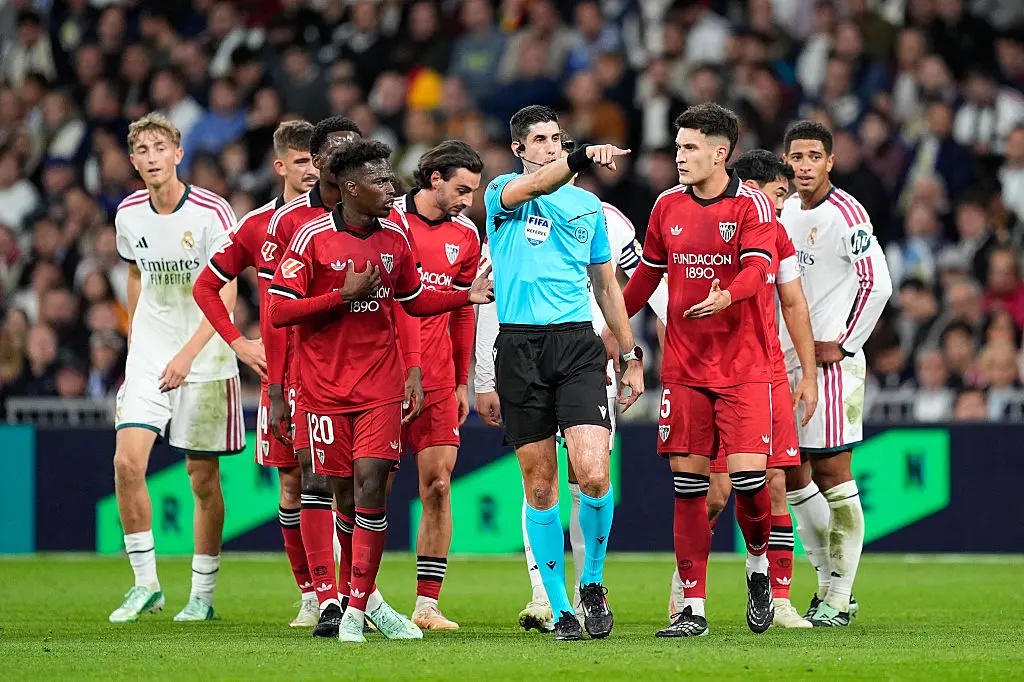 Sevilla players surround referee Mateo Busquets Ferrer