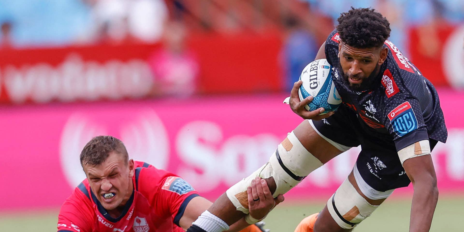 Ein Rugbyspieler der Sharks wird während eines Spiels von einem Bulls-Spieler zu Boden gezogen.