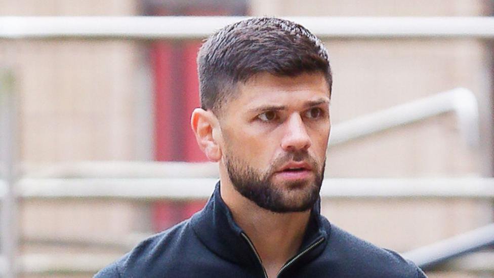 Joe Cordina, a man with brown hair and a short brown beard. He's wearing a navy quarter-zip.