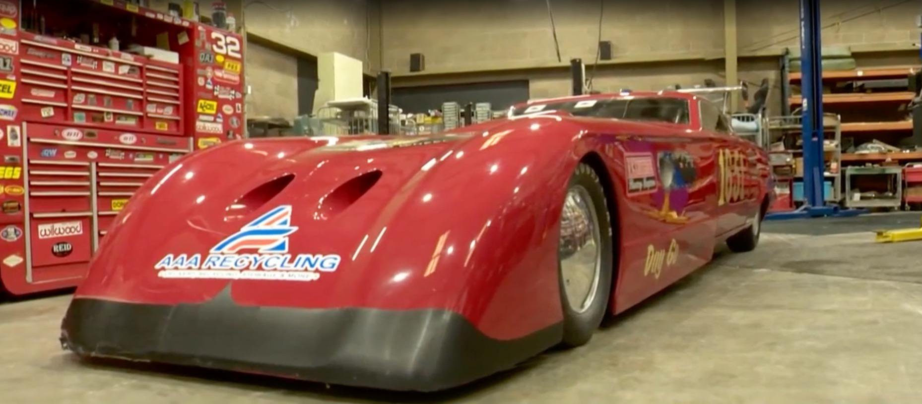A red racing car parked inside a garage.