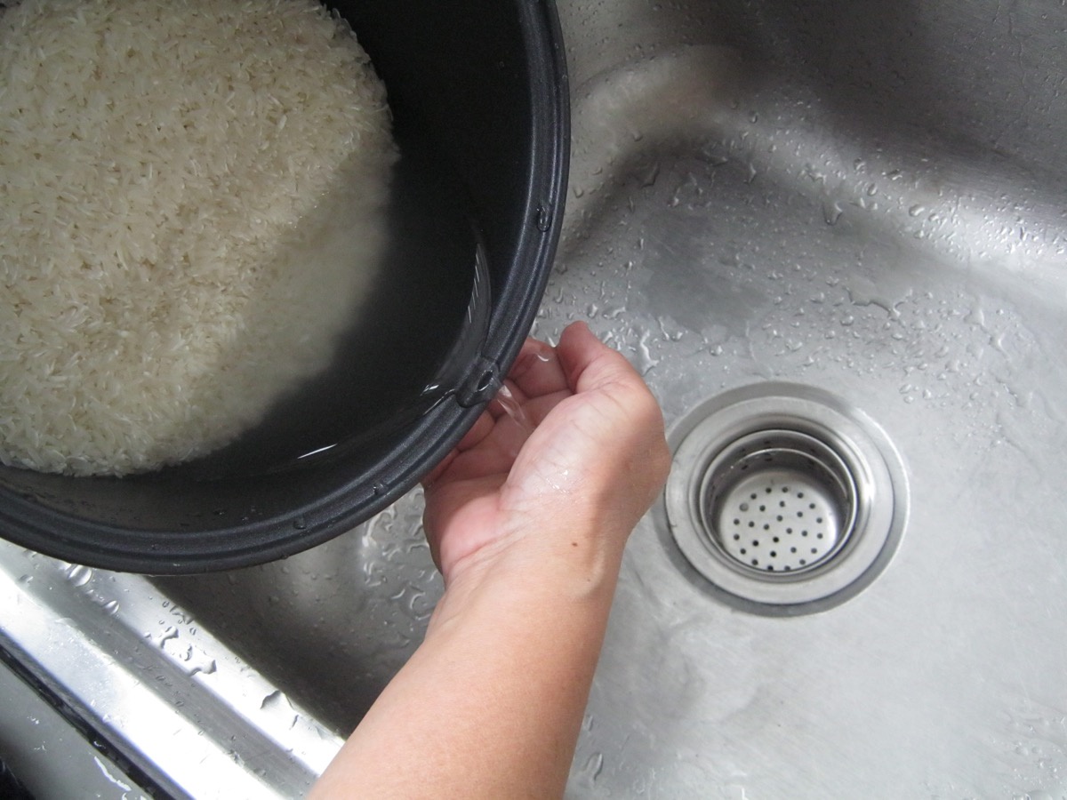 white hands pouring rice into metal sink