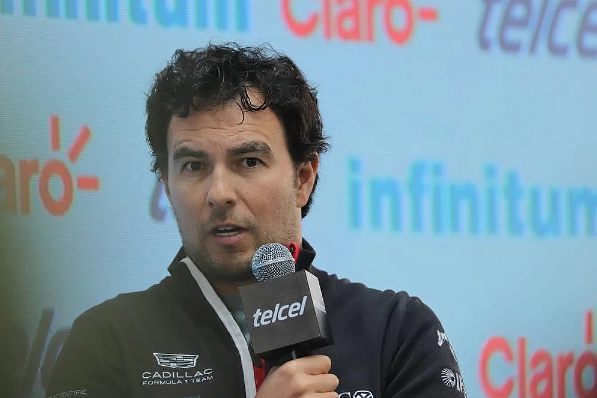 Cadillac Formula 1 driver speaking into a telcel microphone at a press event, with Claro and Infinitum sponsor backdrop
