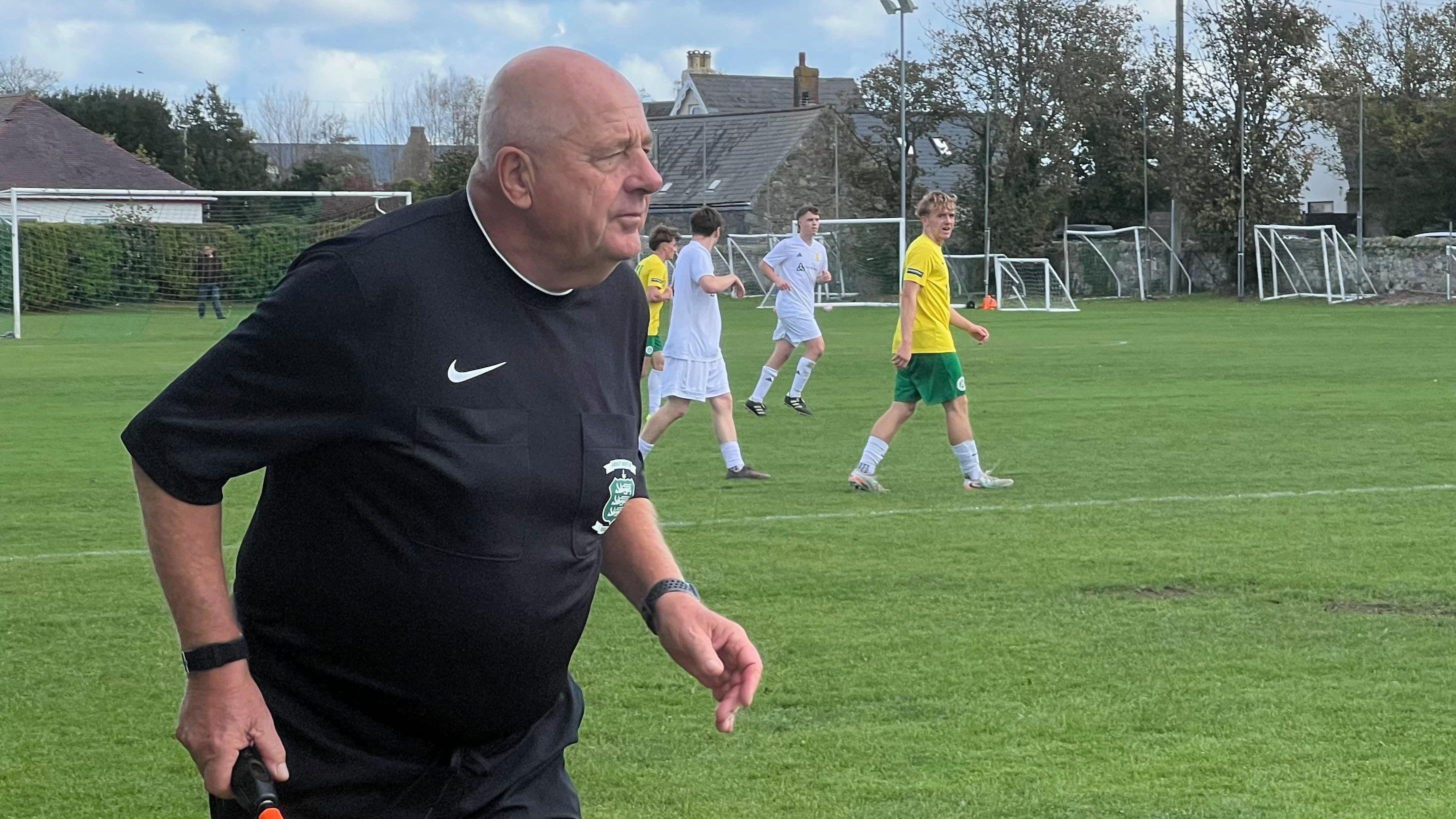 Match official holding a linesman’s flag tracks play during a football game.
