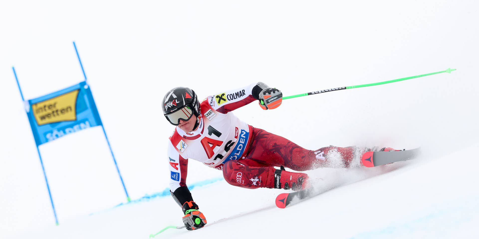 Ein Skirennläufer fährt beim Riesenslalom-Wettbewerb auf einer verschneiten Piste um ein Tor.