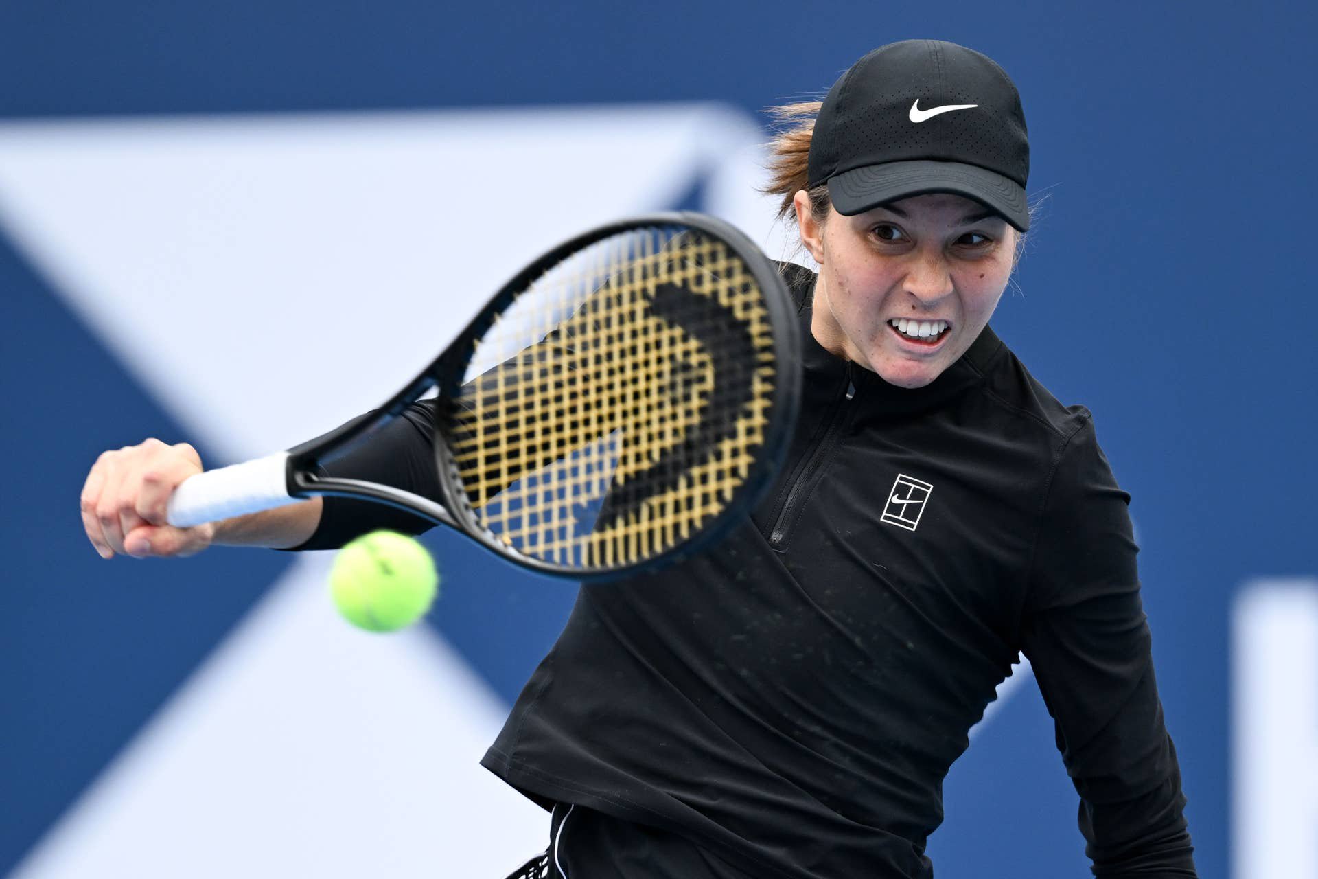 Tennisspielerin schlägt den Ball während eines Matches auf einem Hartplatz.