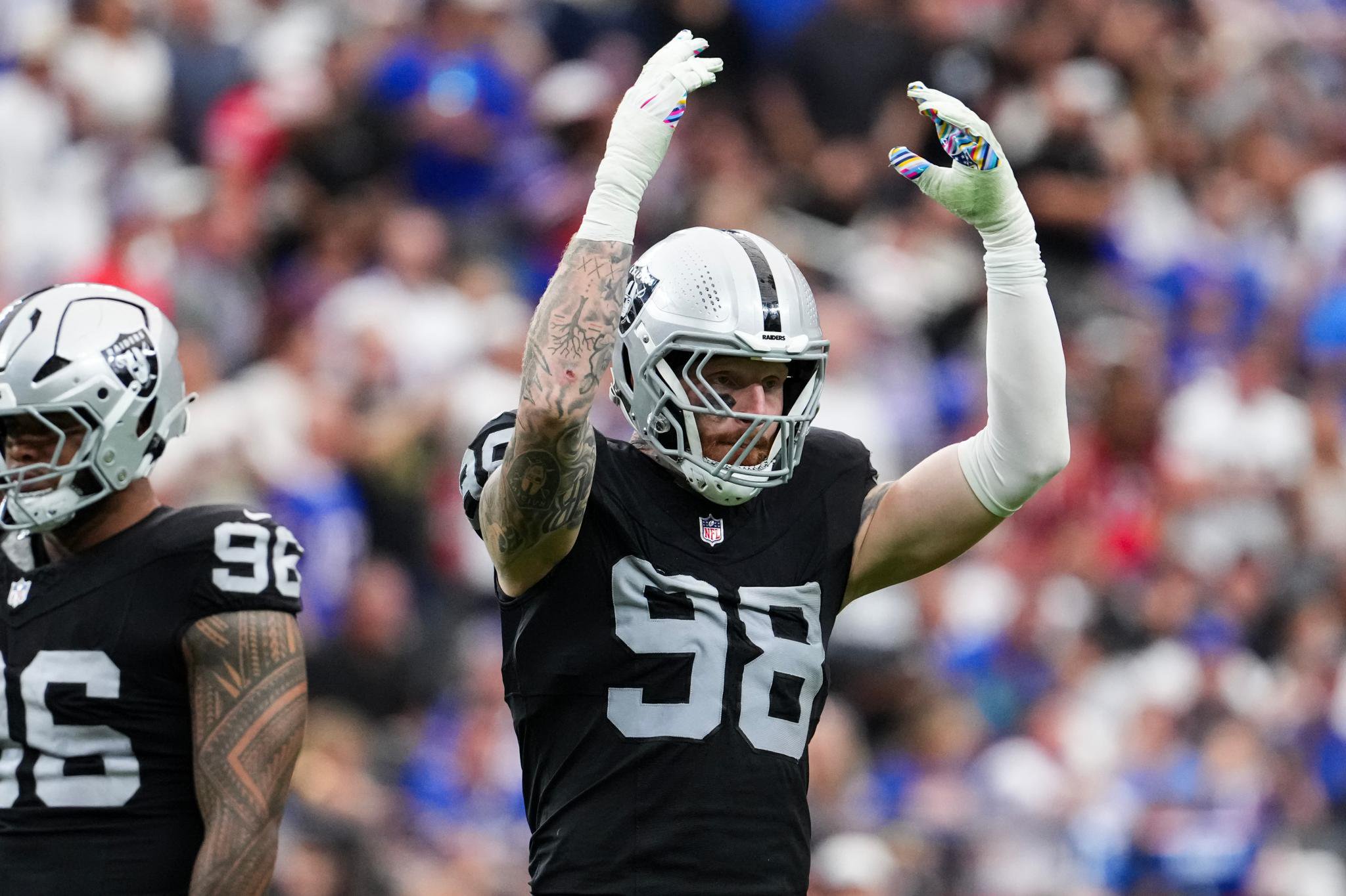Maxx Crosby of the Las Vegas Raiders reacts to the crowd with arms raised during a game against the Buffalo Bills.