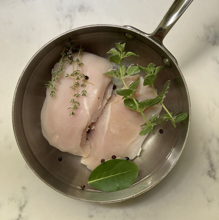 uncooked chicken in a pot with herbs and spices