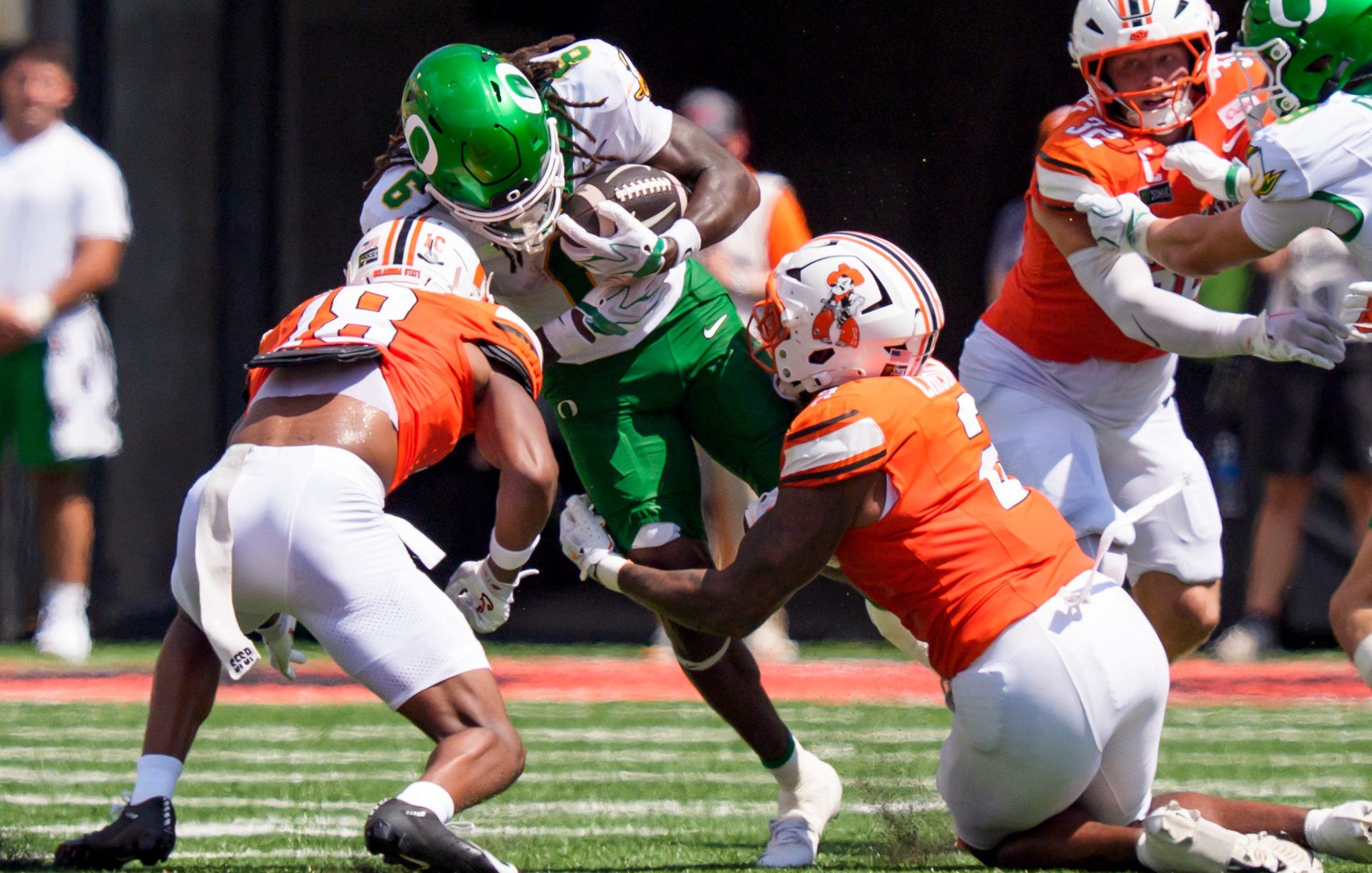 Oregon running back Dierre Hill Jr., center, is brought down by Oklahoma State safety Mose Phillips III, left, and linebacker Isaiah Chisom during their game at Boone Pickens Stadium in Stillwater, Okla.