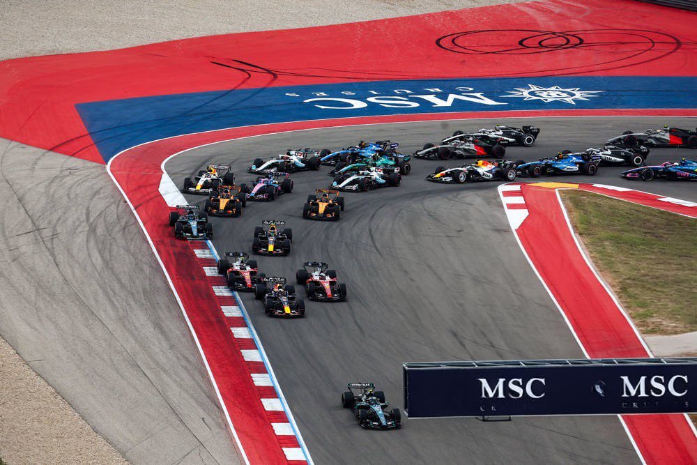 Formula 1 cars racing through a corner at the 2026 US Grand Prix, with Mercedes driver in front on the MSC-branded track, pursued by a pack of rivals