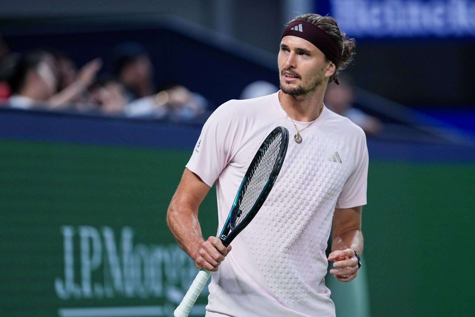 Alexander Zverev steht fokussiert mit dem Tennisschläger in der Hand im hellrosafarbenen Shirt auf dem Court.