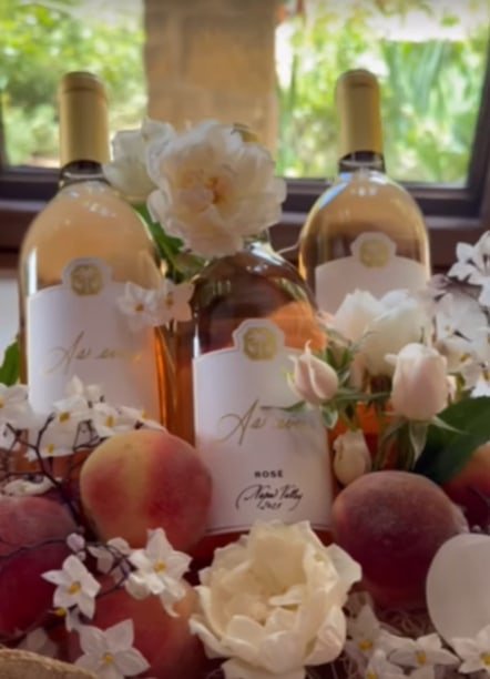 three bottles of rose wine in wooden box surrounded by flowers