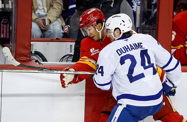 Toronto Maple Leafs' Brandon Duhaime, right, checks Calgary Flames' Zayne Parekh, left, during the third period of an NHL hockey game in Calgary, Alberta, Monday, Oct. 26, 2026. (Jeff McIntosh/The Canadian Press via AP)