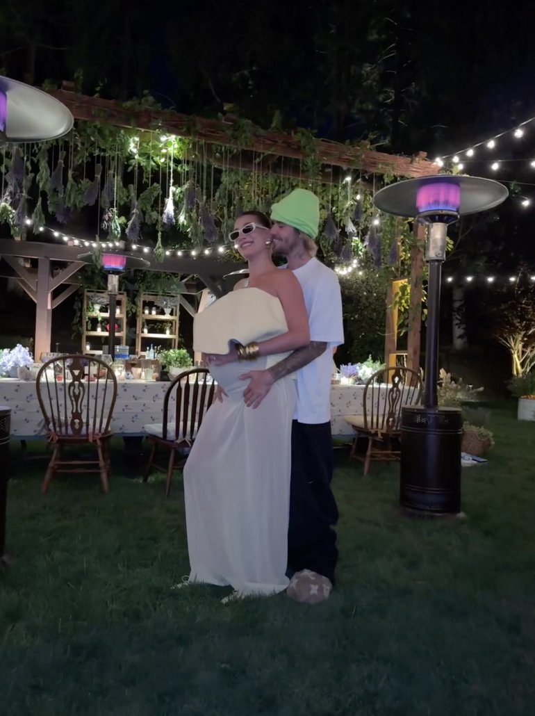 In the video, Hailey Bieber is seen caressing her bump while wearing a sheer, white dress