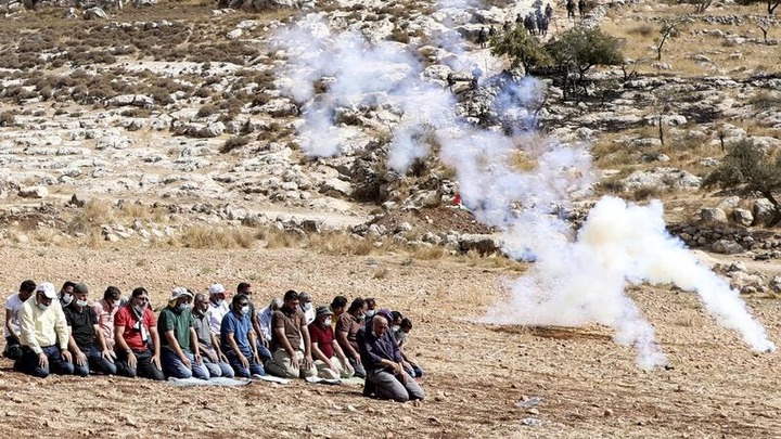 Palestinian protesters pray amidst tear gas smoke fired by Israeli security forces to disperse a demonstration against the expansion of settlements, near the village of Beit Dajan, east of Nablus, on October 9, 2020. JAAFAR ASHTIYEH / AFP