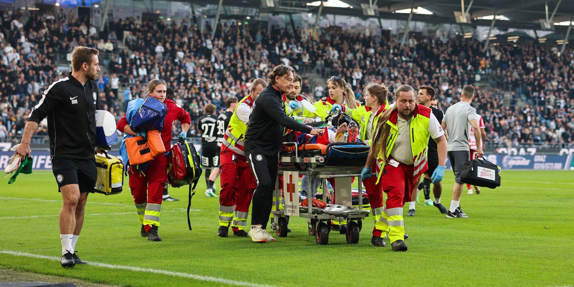 Sanitäter bringen einen verletzten Fußballspieler auf einer Trage vom Spielfeld.