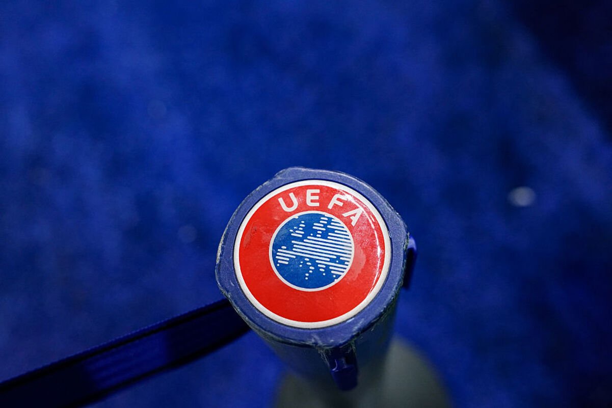 Close-up of a UEFA logo on a blue background, featuring the red circle, blue map of Europe, and white text.