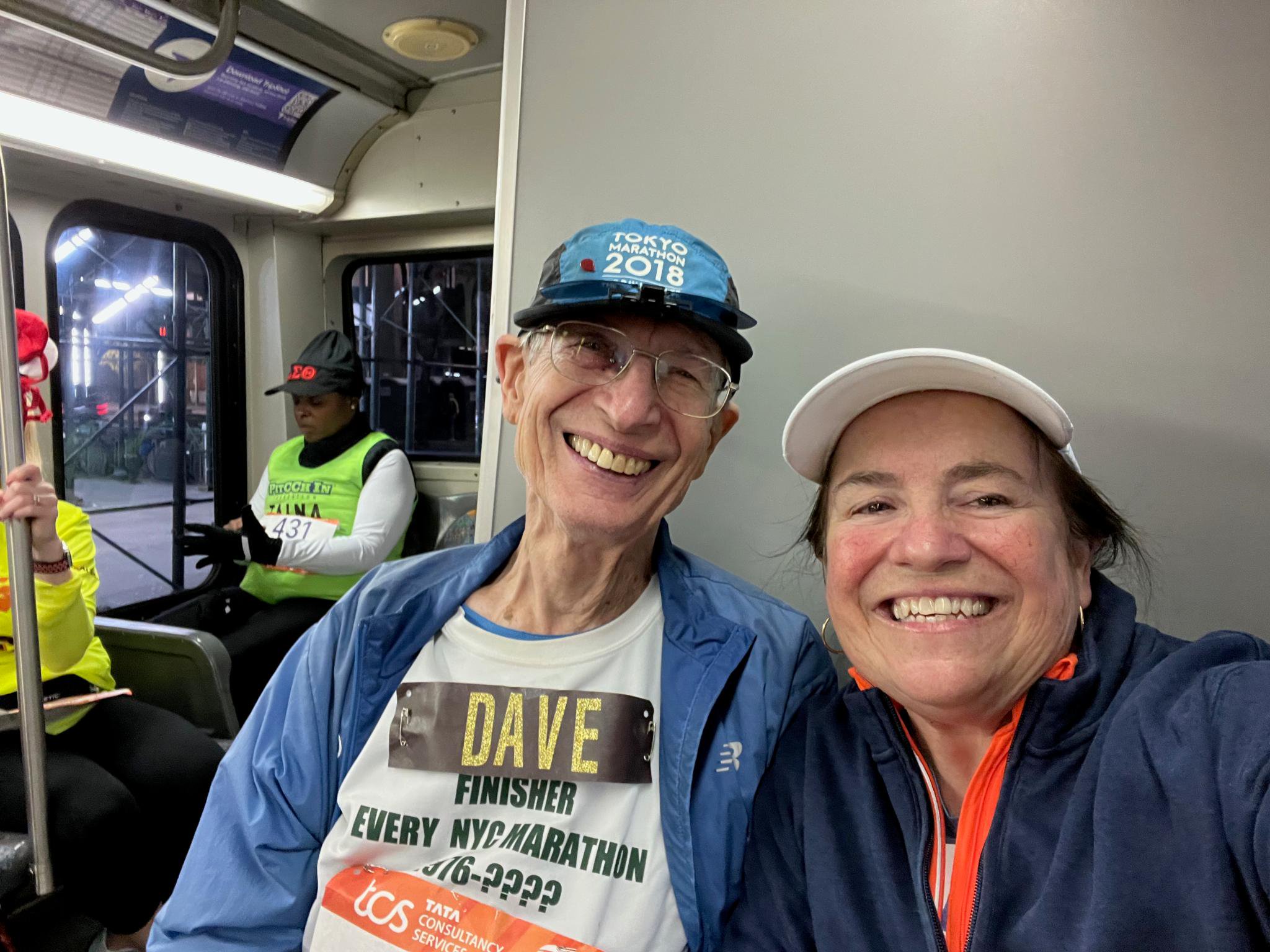 Dave Obelkevich and his daughter and guide, Maria T. Finch, sit smiling on a bus to the marathon start.