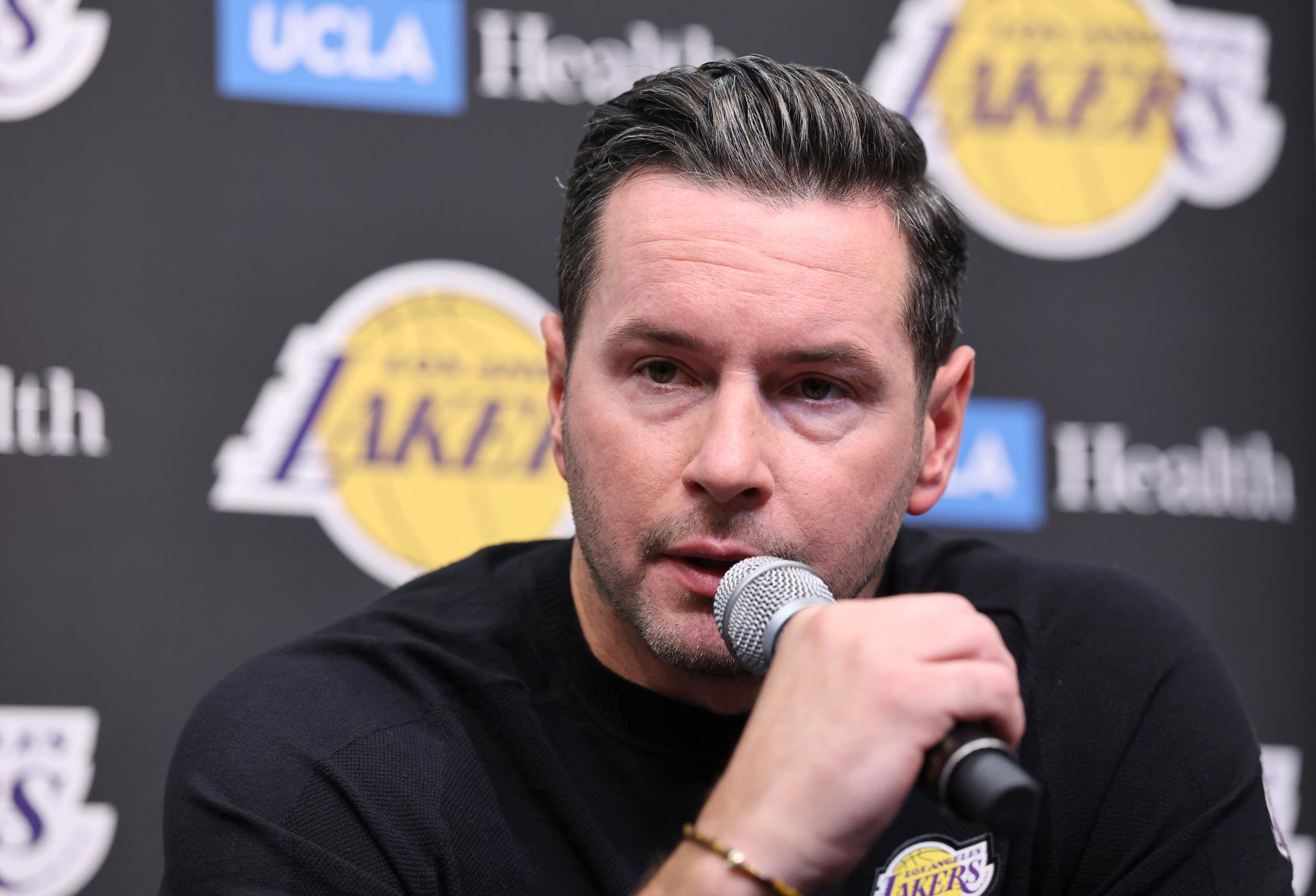 Los Angeles Lakers head coach JJ Redick speaks into a microphone at a news conference.