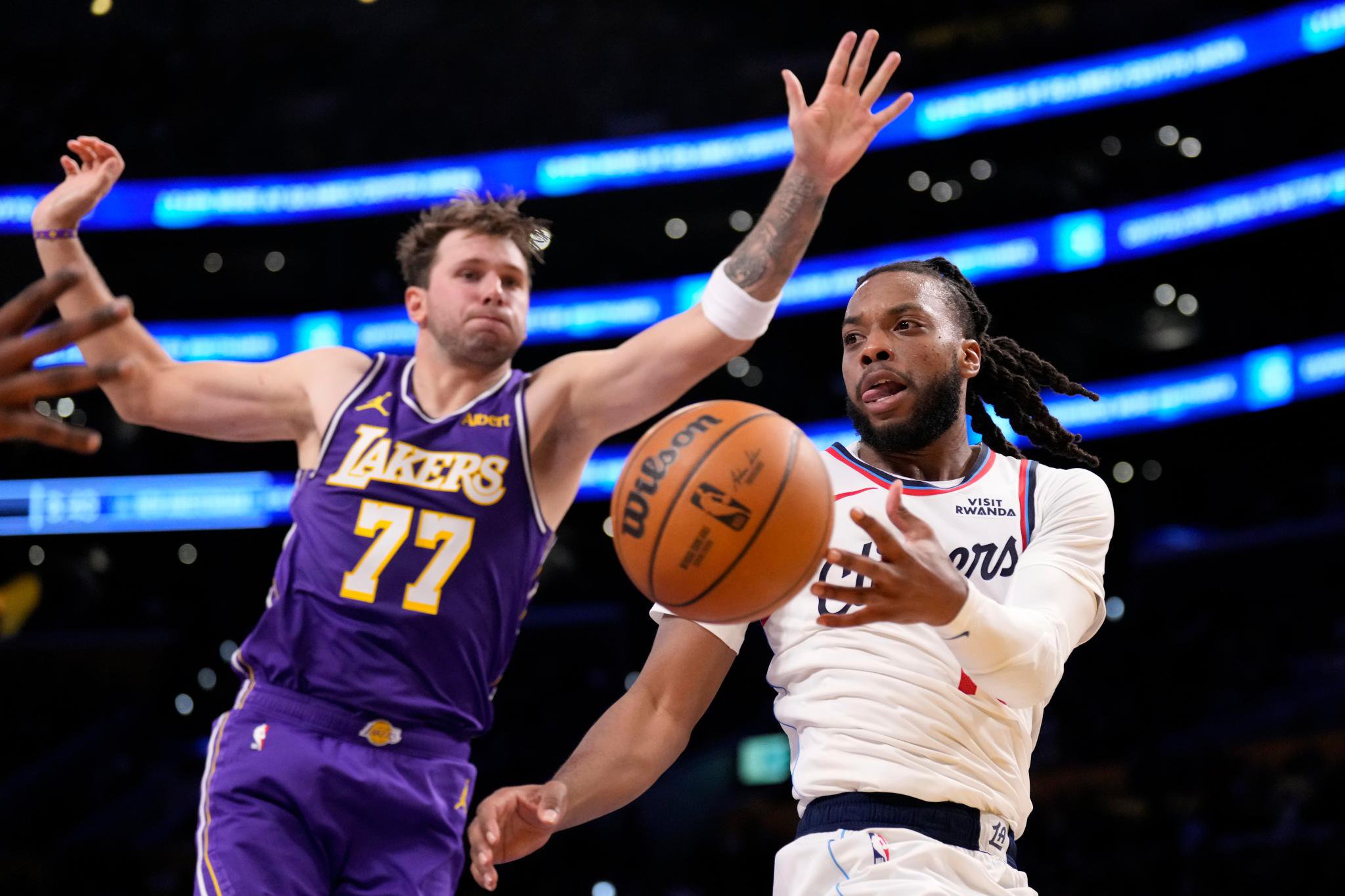 LA Clippers guard Darius Garland passes the ball while under pressure from Los Angeles Lakers guard Luka Doncic.