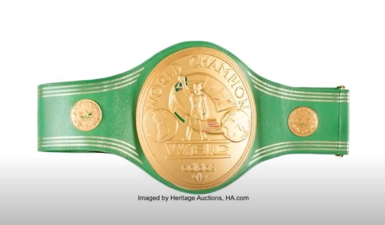 A green and gold championship belt, labeled "World Champion WBC," with intricate designs and logos, is displayed on a white background.