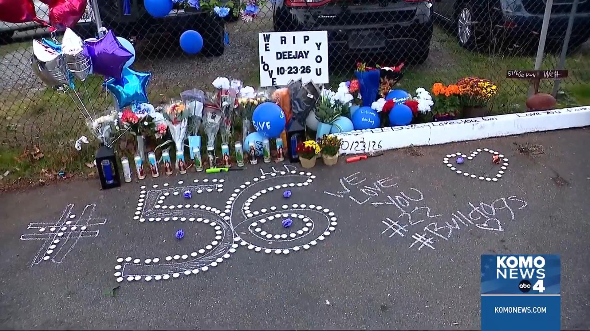 A roadside memorial for Deejay Tuiasosopo features flowers, balloons, candles, and a chalk outline of the number 56.