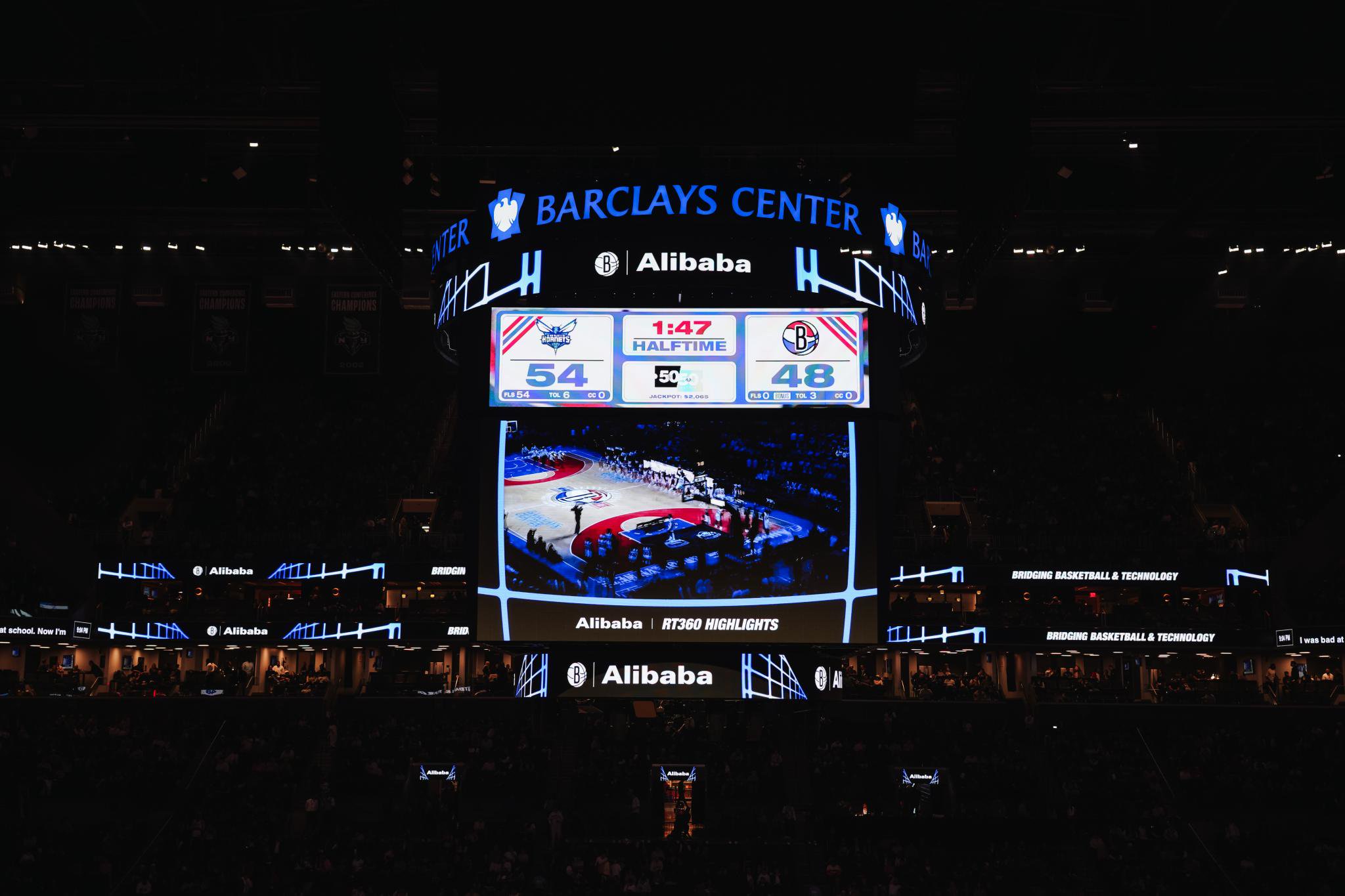 A scoreboard inside the Barclays Center showing a basketball game at halftime with the score 54 to 48.