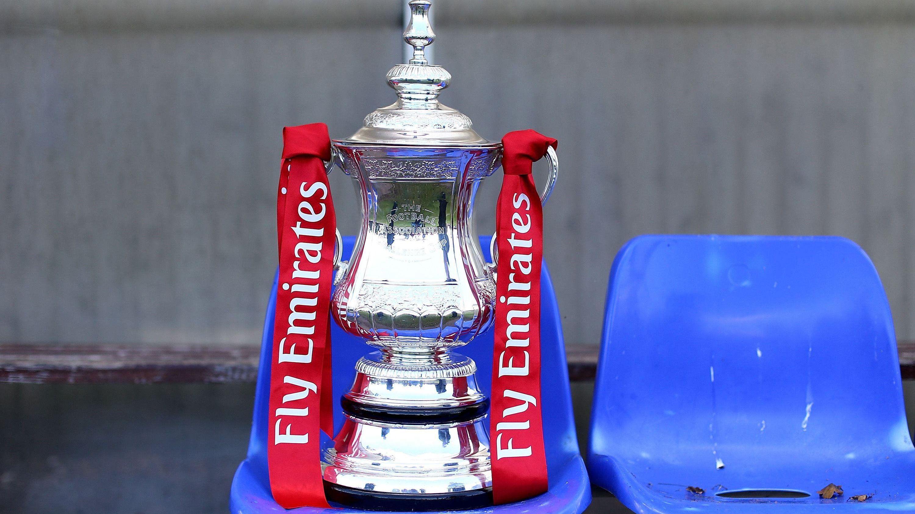 A general view of the FA Cup trophy positioned on a blue plastic seat at a lower league football stadium