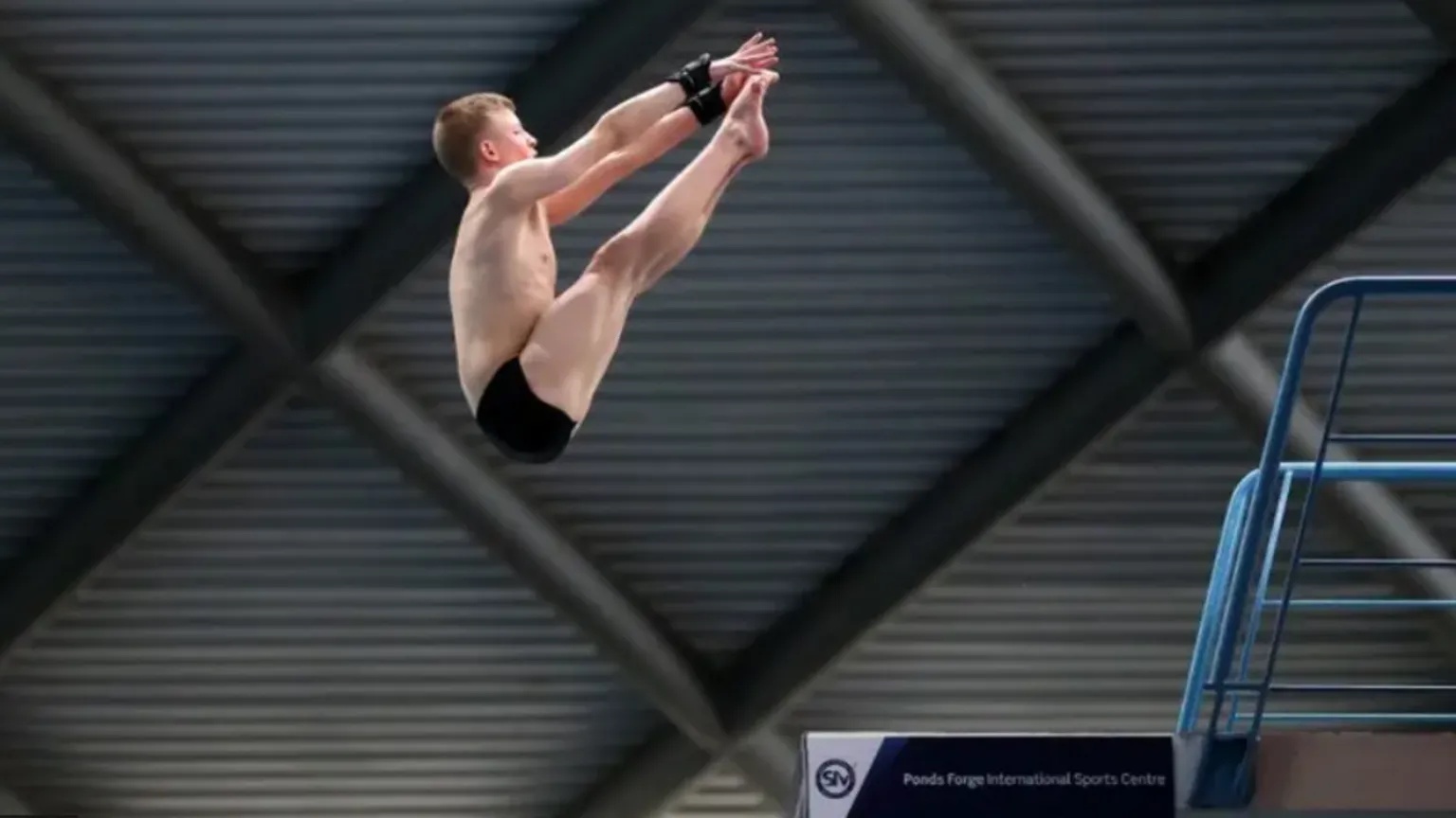 Getty Images A young diver leaps in the air touching his toes off a high board
