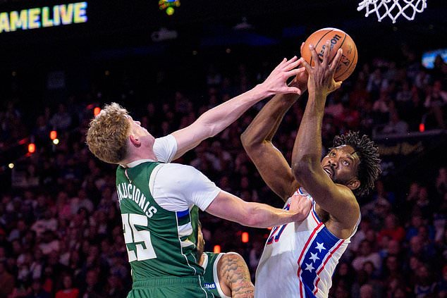 Philadelphia 76ers' Joel Embiid, right, goes up for the shot as he is fouled by Milwaukee Bucks' Kasparas Jakucionis, left, during the first half of an NBA basketball game, Saturday, Oct. 24, 2026, in Philadelphia. (AP Photo/Chris Szagola)