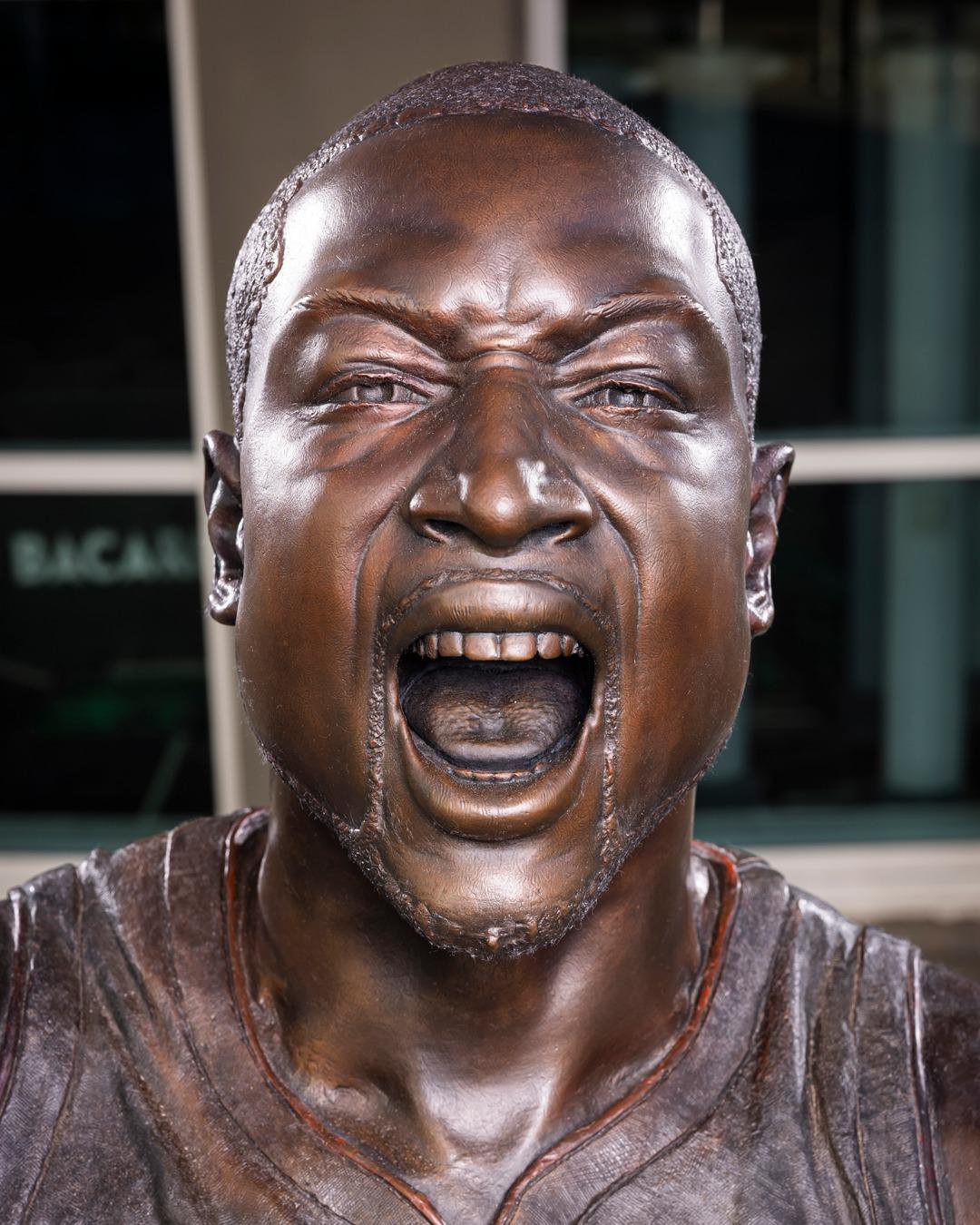 Close-up of the enhanced bronze statue of Dwyane Wade with an open-mouthed expression.