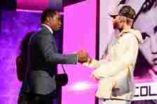 Sean 'P. Diddy' Combs and Justin Bieber shaking hands against a purple background at the 2015 American Music Awards