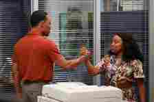 Two actors in character are shaking hands in an office set