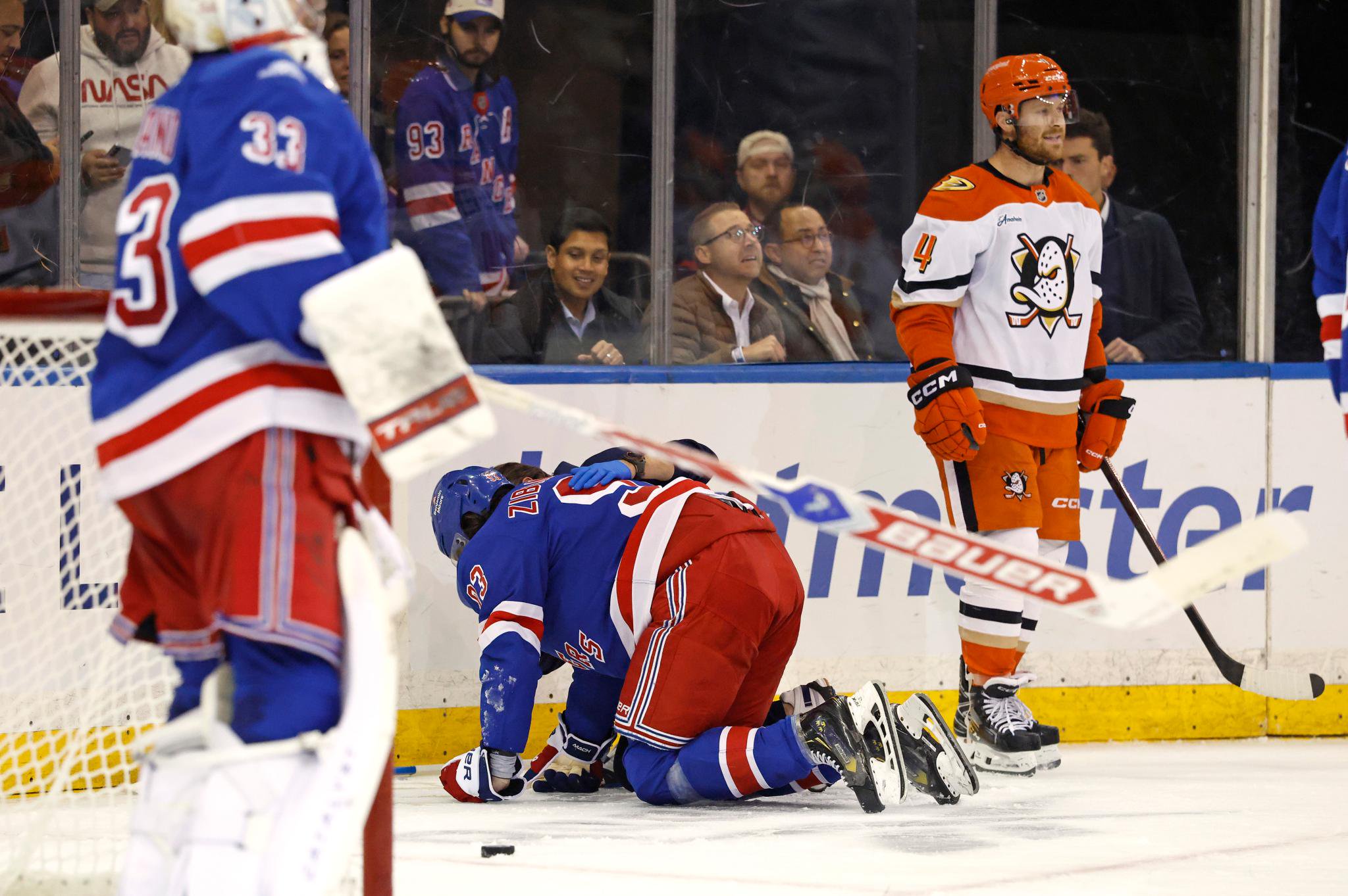 Center Mika Zibanejad of the New York Rangers is checked on by a trainer after taking a hard hit during an NHL hockey game against the Anaheim Ducks.