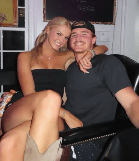 A young couple sitting together indoors, smiling at the camera.
