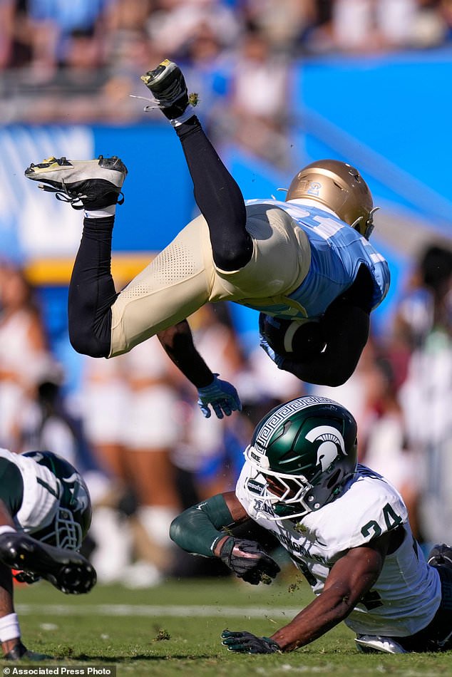 UCLA running back Jaivian Thomas, top, is upended by Michigan State cornerback Jeremiah Favorite during the second half of an NCAA college football game, Saturday, Oct. 24, 2026, in Pasadena, Calif. (AP Photo/Mark J. Terrill)