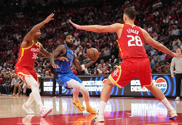 Dallas Mavericks guard Kyrie Irving, center, controls the ball against Houston Rockets' Marcus Smart (36) and Alperen Sengun (28)during the first half of an NBA basketball game, Wednesday, Oct. 21, 2026, in Houston. (AP Photo/Karen Warren)