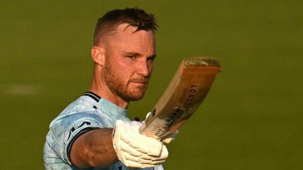 Laurie Evans in a blue and white patterned Surrey kit lifts his bat.