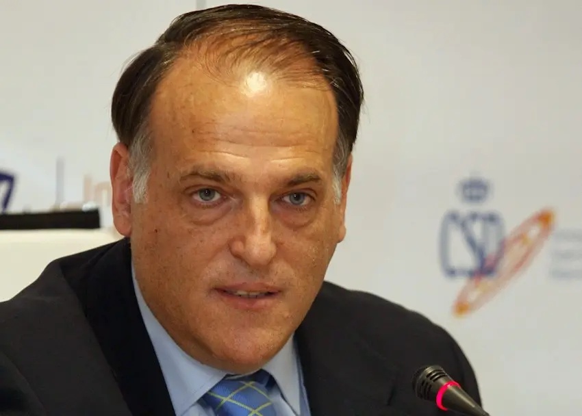 Portrait of Javier Tebas wearing a dark suit and blue tie, speaking at a press event.