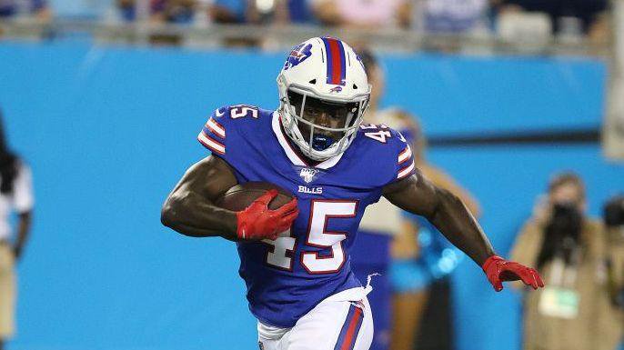 Christian Wade, wearing number 45, playing for Buffalo Bills. He is wearing red gloves and has the football under his right arm