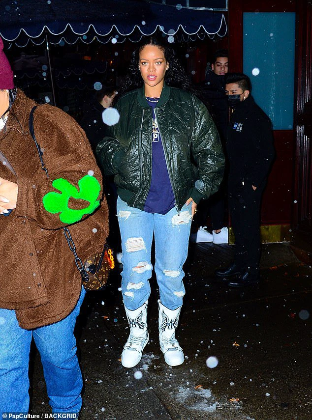 Staying warm: Rihanna wore a blue crewneck sweater underneath a dark green puffy jacket during her outing.