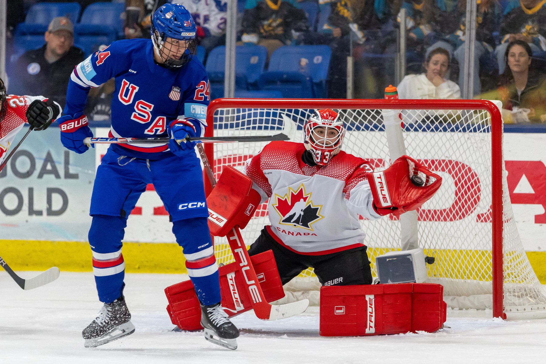 Team Canada's Ève Gascon (37) makes a glove save as Team USA's Joy Dunne (24) attempts to tip the shot during the first period.