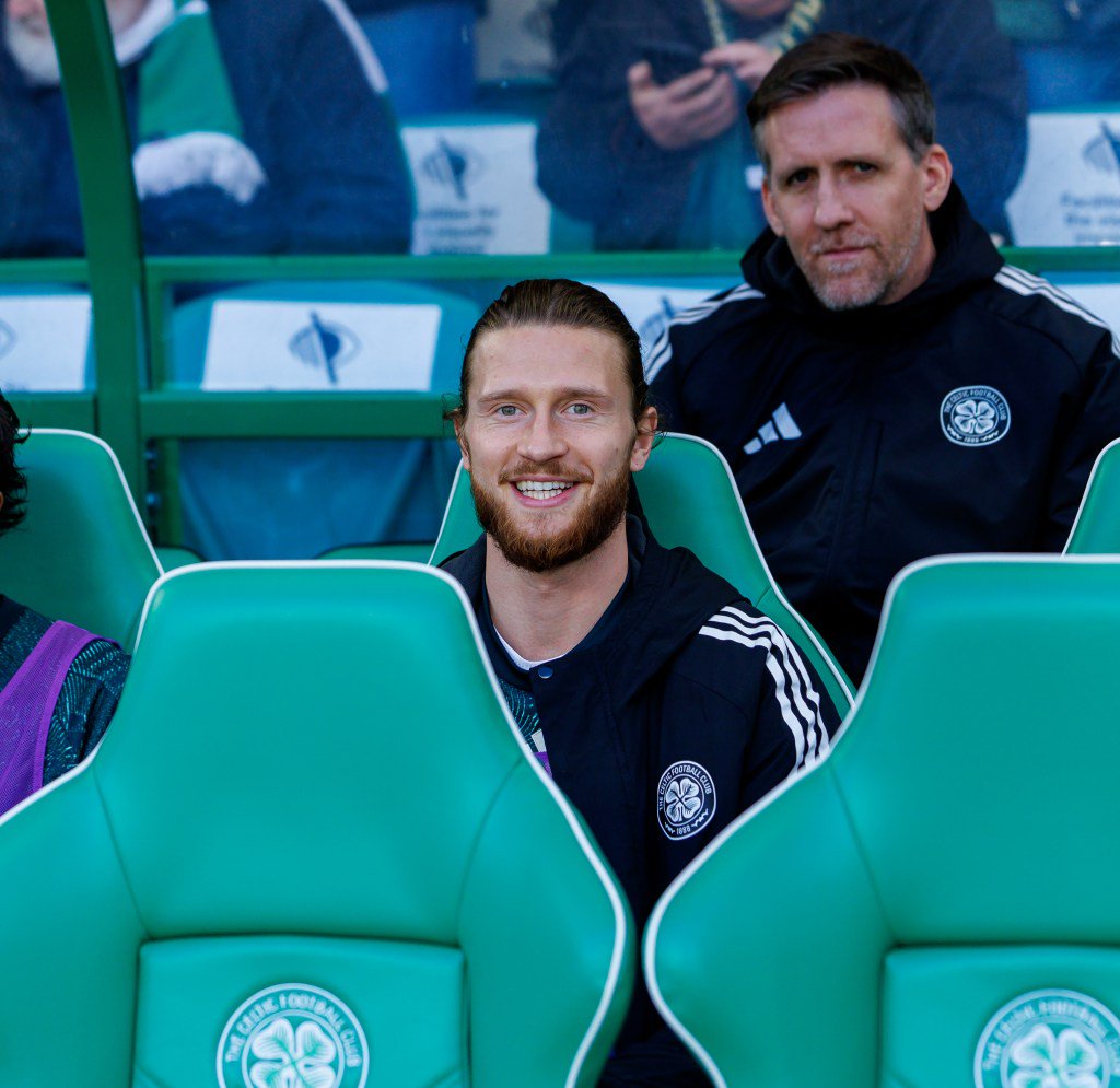 Kasper Hogh sits smiling on the substitutes' bench during a match against Celtic.