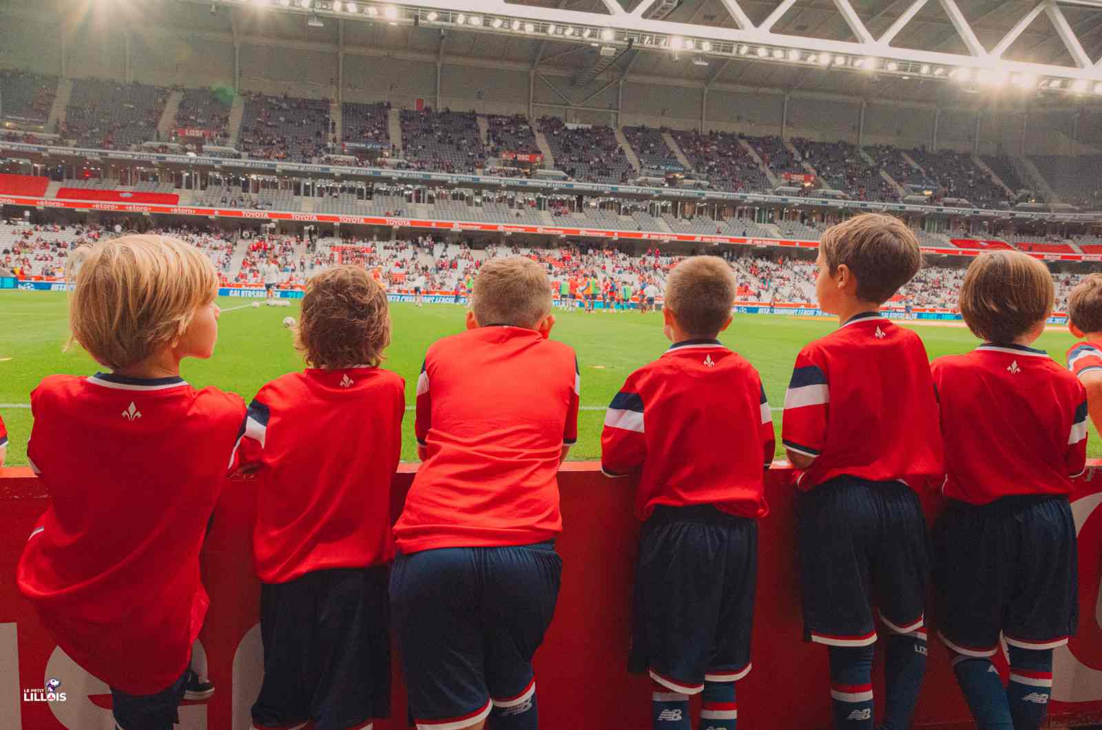 Des jeunes qui regardent l'échauffement des Dogues depuis le bord de pelouse.