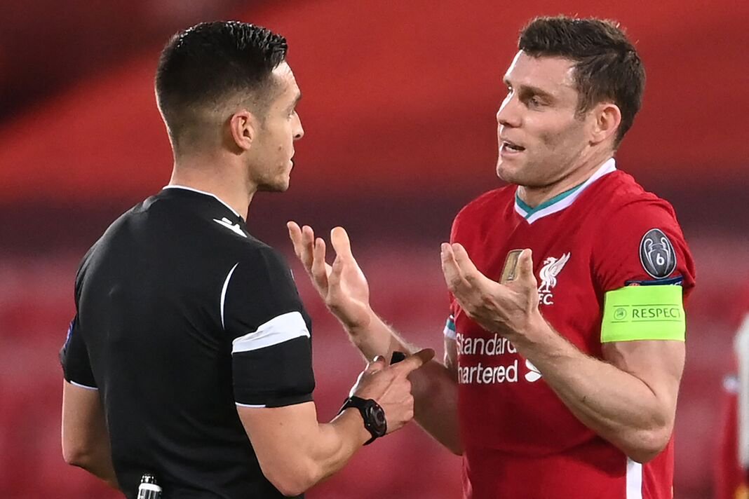 Liverpool captain James Milner speaks to referee